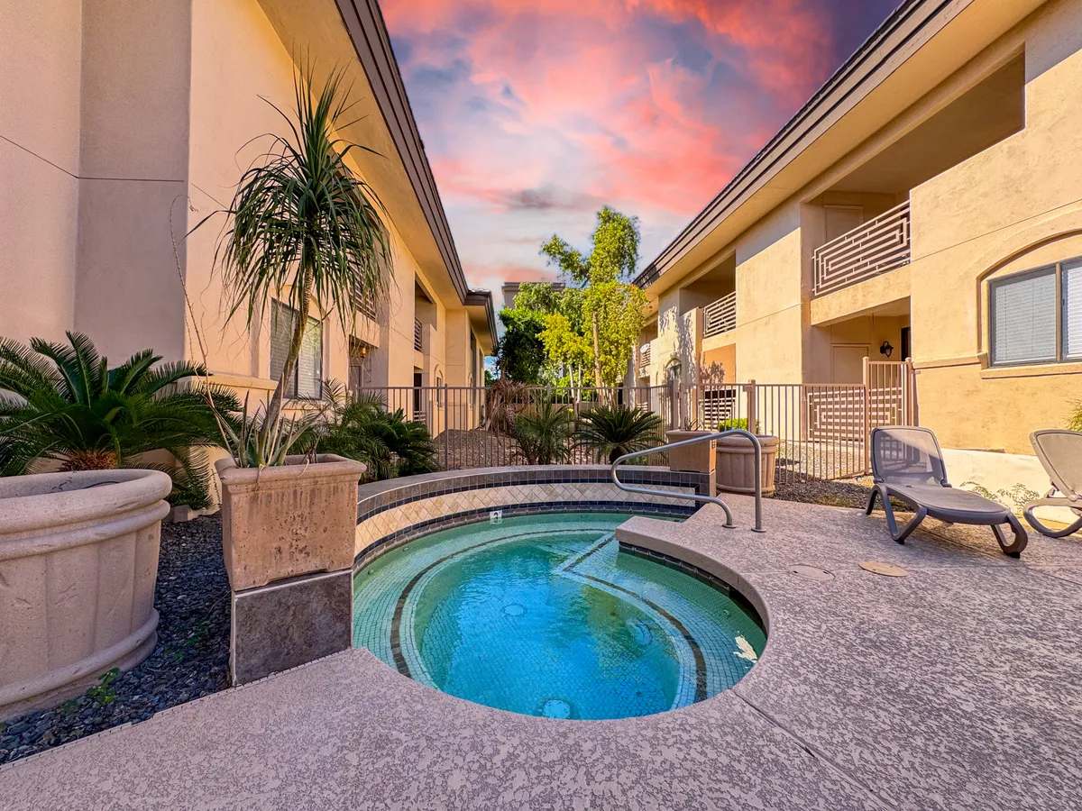 A serene spa area framed by lush greenery and modern building architecture. The spa’s inviting waters are highlighted by the soft hues of the setting sun, suggesting a peaceful spot for evening relaxation or a quiet moment together.