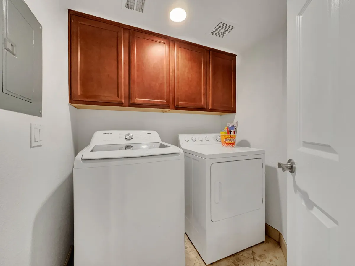 A dedicated laundry area showcasing a washer and dryer set beneath built-in cabinets. The layout is clean, organized, and practical, emphasizing day-to-day convenience for guests.