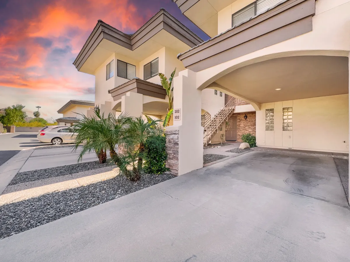 The exterior of the community is shown with palm trees, stone accents, and a staircase entrance, offering a glimpse of secure access and the inviting environment of the complex.