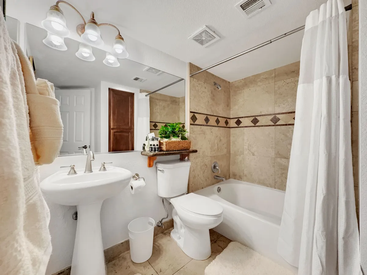A calm, refreshing bathroom with a bathtub, sink, mirror, light fixtures, and a towel rack. The space is bright and clean, offering a soothing environment ideal for unwinding after a long day.